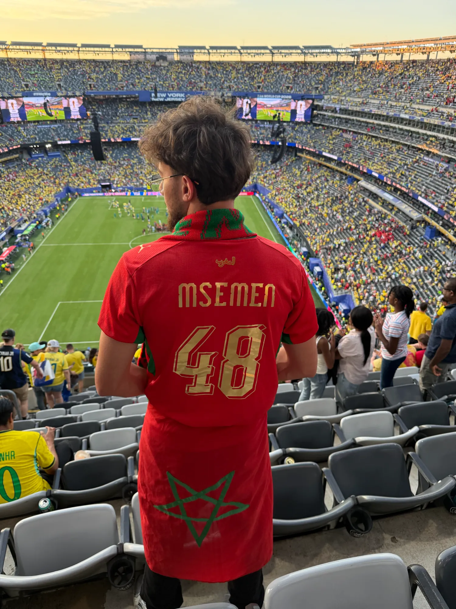 Supporter de dos portant un maillot rouge du Maroc floqué MSEMEN 48, dans les tribunes d'un stade de la Coupe du Monde 2026 à New York New Jersey